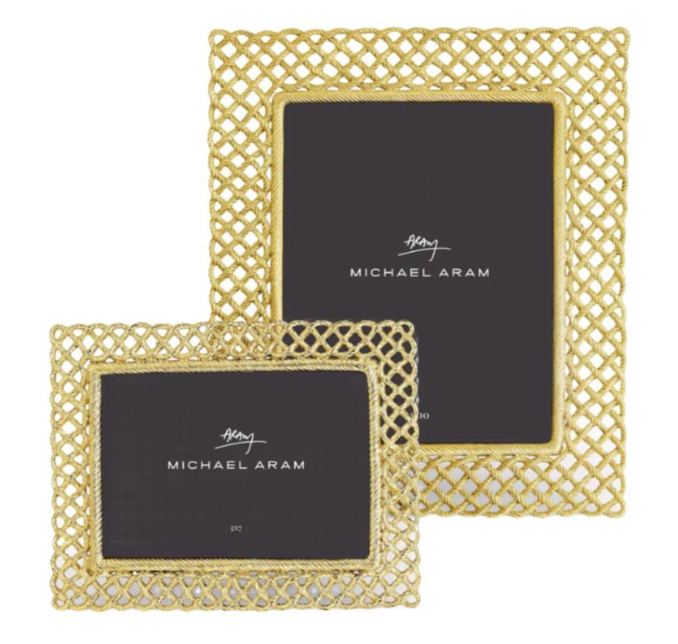 The Michael Aram Love Knot Gold Frame Collection features two gold lattice-patterned frames of different sizes, each with a "Michael Aram" signature card, symbolizing unity in their elegant design.