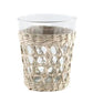 The Be Home Seagrass Cage Glassware Collection features a clear glass cup with a woven seagrass rattan holder around the base, ideal for adding style to your glassware display, shown here against a white background.