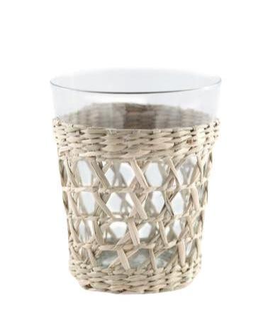 The Be Home Seagrass Cage Glassware Collection features a clear glass cup with a woven seagrass rattan holder around the base, ideal for adding style to your glassware display, shown here against a white background.