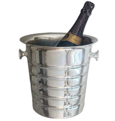 A bottle of champagne is chilling in a Hôtel Silver Vintage Champagne Bucket with Flared Top & Ribbed Body, featuring handles on each side.