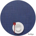 A red spoon, white saucer, and empty cup are arranged on a Chilewich round placemat from the Round Placemat Collection, crafted with phthalate-free Terrastrand yarns.