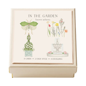 Karen Adams’ “In the Garden Gift Enclosures” features a cream-colored box with hand-glittered illustrations of a moth, flowers, topiary, and fountain. Includes 8 enclosure cards and 8 envelopes.