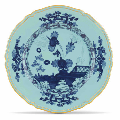 The Oriente Italiano Iris with Gold Dinnerware & Decor Collection by Ginori 1735 features a porcelain plate with a scalloped edge, light blue background, dark blue floral and geometric patterns, and a gold rim for an elegant touch.