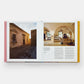 The open book, "Italian Interiors: Rooms with a View" by Phaidon, features images of rustic architecture: a stone courtyard graces the left page, while the right page showcases an interior with arched walls and wooden furniture that embodies Italian interior design.