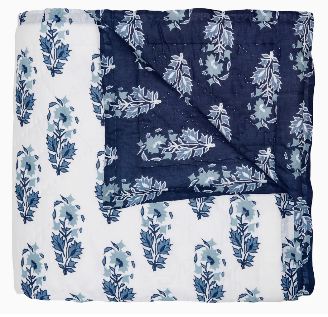 The Kanak Indigo Bedding Collection by John Robshaw features a hand-quilted cotton quilt with indigo and white leaf block print on one side and dark blue with lighter blue leaves on the reverse.