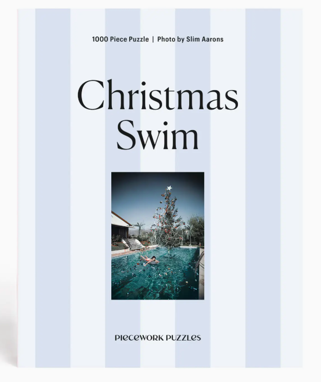 The Piecework Slim Aarons Puzzle Collection includes a 1000-piece jigsaw puzzle featuring “Christmas Swim,” showcasing a vibrant photograph of a swimmer in a pool with a Christmas tree beneath a bright sky. Crafted from high-quality art paper and recycled paper, this puzzle combines beauty with eco-friendly materials.