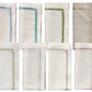 The Kim Seybert Jardin Napkin Set includes eight folded linen napkins, each with a unique embroidery border in neutral tones, arranged in two rows on a white background.