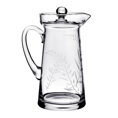 The Jasmine Pitcher Collection by William Yeoward Crystal features a clear glass pitcher with handle and lid, adorned with an elegant leaf and branch etching reminiscent of a cherished wedding gift or jasmine’s delicate beauty.