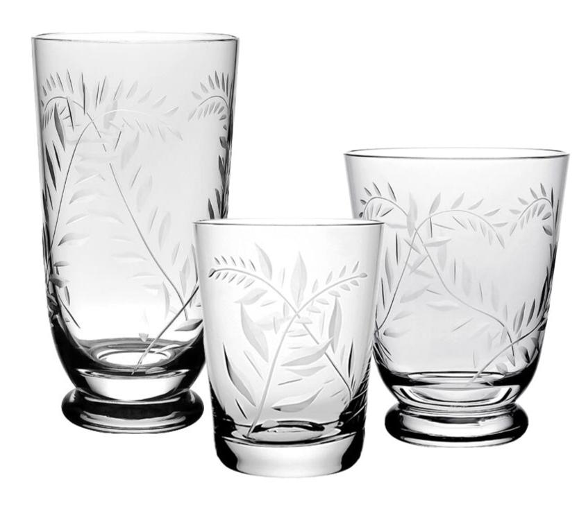 The Jasmine Collection by William Yeoward Crystal features three clear glasses of different heights, each with etched leaf patterns, elegantly displayed as luxurious handmade glassware for sophisticated table settings.
