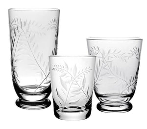 The Jasmine Collection by William Yeoward Crystal features three clear glasses of different heights, each with etched leaf patterns, elegantly displayed as luxurious handmade glassware for sophisticated table settings.