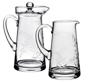The Jasmine Pitcher Collection by William Yeoward Crystal features two clear glass pitchers with engraved fern leaves, one lidded and one open—an elegant pair displayed side by side, perfect as a treasured wedding gift.