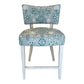 The A. Rudin Counter Stool in Turquoise Shell Grato features white wooden legs and a padded seat and backrest upholstered in green and white grato fabric with an intricate seashell and coral motif.