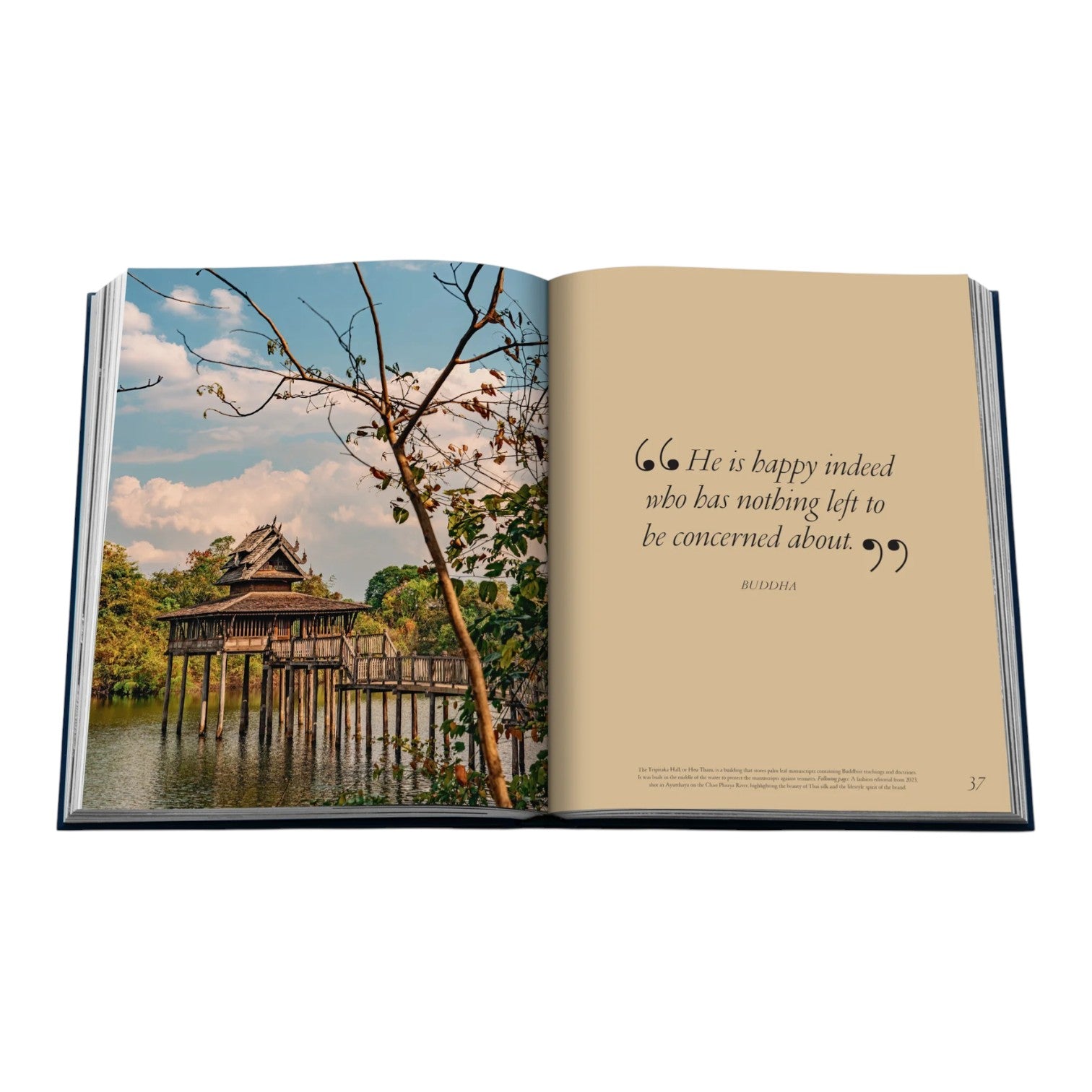 An open book, "Jim Thompson, Beyond Silk, Beyond Thailand" by Assouline, shows a lakeside wooden structure photo on the left page and a Diogenes quote about happiness on the right, reflecting tranquil Asian living.