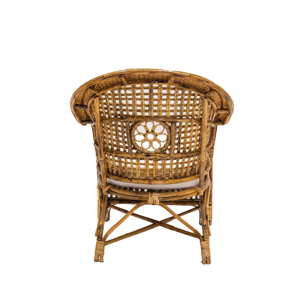 The Julianna Occasional Chair by Varnish Collection features a back view of artisanal rattan with a woven lattice and central circular floral pattern, plus a light seat cushion—crafted from natural materials.