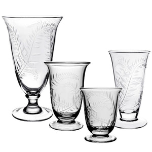 Four vases from the Jasmine Flower Vase Collection by William Yeoward Crystal, featuring handmade etched leaf designs inspired by a jasmine vine motif, are displayed in a row against a white background.