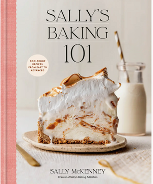 Cover of *Sally’s Baking 101* by Penguin Random House, inspired by Sally’s Baking Addiction, showcasing a generous slice of meringue-topped pie on a plate beside a glass of milk with a striped straw—a mouthwatering introduction to irresistible baking recipes and homemade treats.