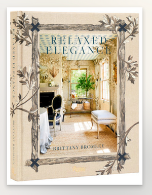 Book cover of "Relaxed Elegance: Rooms for Living Well" by Rizzoli, displaying a bright, elegant room with traditional decor and patterned wallpaper—highlighting classic Palm Beach style with tall windows.