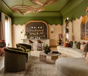 Elegant living room with green walls, plush furniture, and a stylish bar area, accented by the unique Indonesian Bamboo Chandelier from Balsamo Antiques and arched doorways at the Kips Bay Show House.