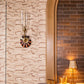 A wall-mounted sconce with a glass shade is paired with the Poldina Pro Lamp from Zafferano America, placed on a marble countertop alongside a glass and basket, in front of dark brown brick tiles and patterned wallpaper.