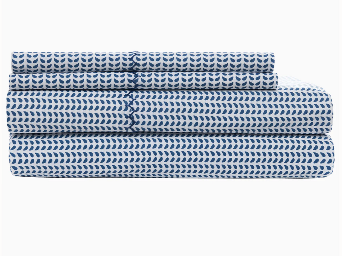 A neatly folded stack of bed sheets from the John Robshaw Cinde Bedding Collection, featuring a light indigo Cinde print in blue and white, arranged against a plain white background.