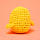 Kiki the Chick Beginner Crochet Kit by The Woobles features a small, round, yellow crochet chick with two short arms, set against a plain peach-colored background—an ideal project for beginner crochet enthusiasts or as part of a complete crochet kit.