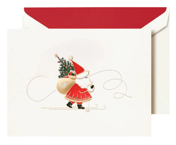 Crane's Skiing Santa Card Set showcases a charming Christmas card with a small Santa skiing while holding a sack and a adorned Christmas tree, all set against the backdrop of a red envelope.