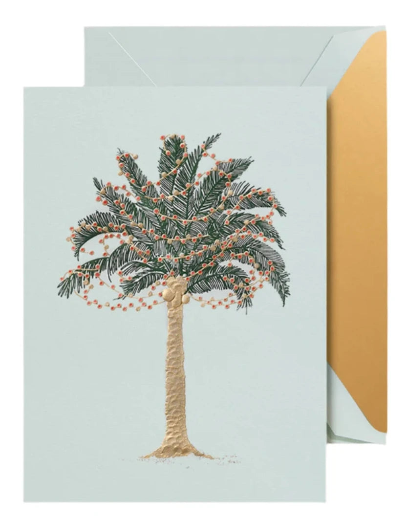 The Crane Twinkling Palms Card Set features an embossed palm tree with orange lights and includes a beautiful beach glass blue card with a gold-lined matching envelope.