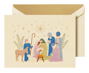The Crane Nativity Christmas Card Set features a cream-colored card with a Nativity scene—Mary, Joseph, baby Jesus in a manger, wise men, shepherd, lamb, donkey, and stars—ideal for celebrating the holiday season.