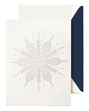 The Crane Silver Snowflake Card Set features an embossed white snowflake card, ideal for the holidays, shown partially inside a white envelope with a dark blue lining.