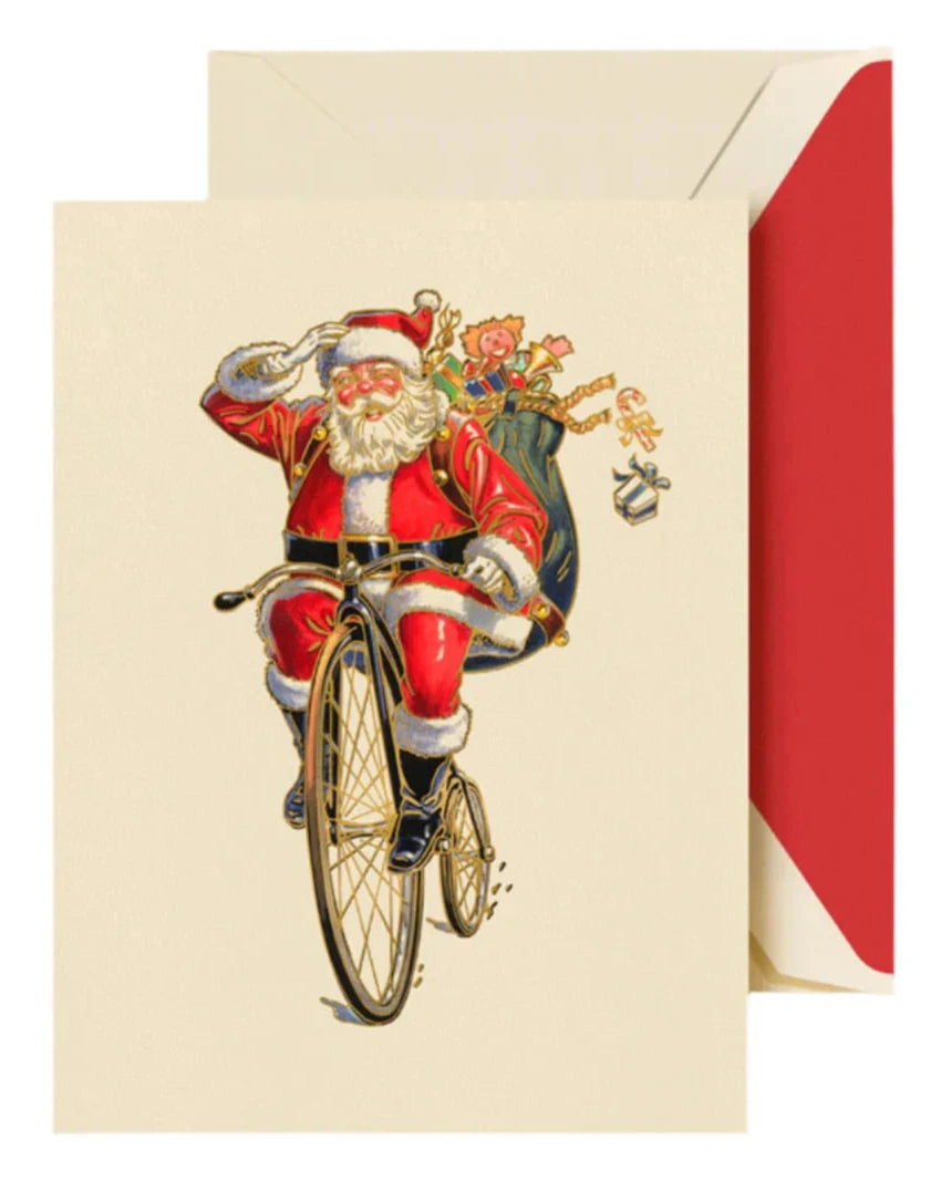 The Crane Penny Farthing Santa Card Set by Crane showcases a vintage-style card with Santa Claus joyfully riding a bicycle, his sack overflowing with Christmas presents, all beautifully displayed on the front of an enchanting greeting card accompanied by a festive red and white envelope.