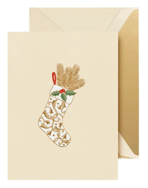 The Regal Stocking Card Set by Crane includes cream-colored holiday cards featuring a gold-patterned Christmas stocking with pine and holly, paired with matching envelopes.