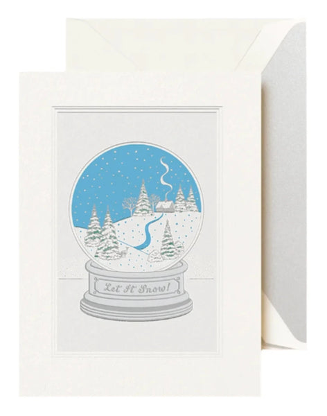 The Crane Snow Globe Card Set by Crane features a winter scene of trees, snow, and a path inside a snow globe. "Let it Snow!" is inscribed on the base, wishing recipients a Merry Christmas with this distinctive card design.