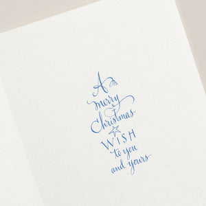 Send warm wishes with Crane's Snow Globe Card Set, featuring a unique design with blue cursive text reading "A merry Christmas wish to you and yours" on elegant white paper.