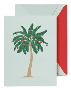 The Trimmed Palm Tree Card Set by Crane features a tropical palm tree decorated with red ornaments, paired with a festive red-lined envelope.