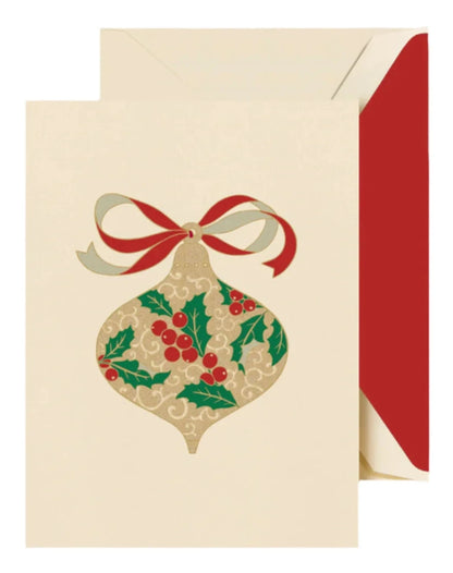 The Crane Filigree Ornament Card Set includes holiday greeting cards with engraved filigree ornaments, holly leaves, red berries, and a red and gold ribbon, paired with cream envelopes featuring festive red linings.
