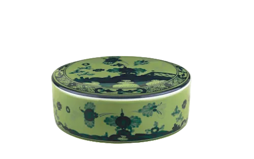 A round green ceramic box with a fitted lid, featuring dark blue floral and geometric designs inspired by Ginori 1735’s Oriente Italiano Malachite Dinnerware Collection.