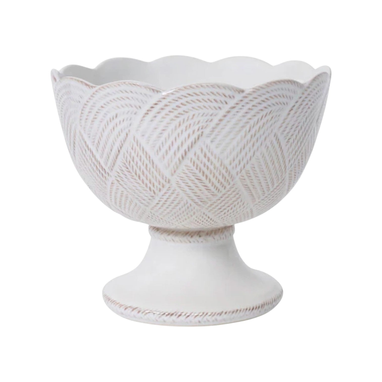 The Le Panier Mystic Knot Collection by Juliska features a white ceramic pedestal bowl with a scalloped rim and textured, geometric pattern inspired by French basket weave.