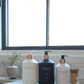 Three soap and lotion pump bottles on a L’Avant Collective Lucite Soap & Candle Tray resting on a marble countertop.