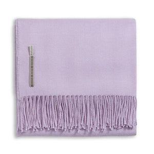 Folded light purple fringed baby alpaca blanket from the Alicia Adams Alpaca Classic Throw Collection, featuring a fabric label near the edge, fair-trade made in Peru, displayed on a white background.