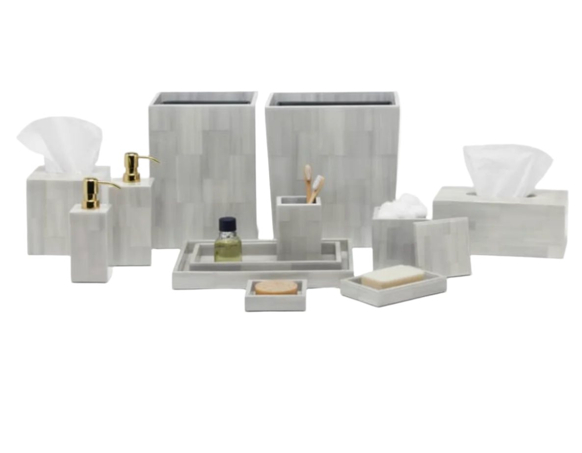 The Arles Bath Collection by Pigeon & Poodle features sleek, gray marble-patterned accessories—tissue box, soap dispenser, tray, and container—arranged on a white background. Inspired by classic faux horn bath sets.