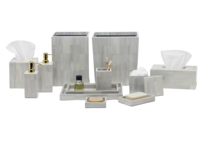 The Arles Bath Collection by Pigeon & Poodle features sleek, gray marble-patterned accessories—tissue box, soap dispenser, tray, and container—arranged on a white background. Inspired by classic faux horn bath sets.