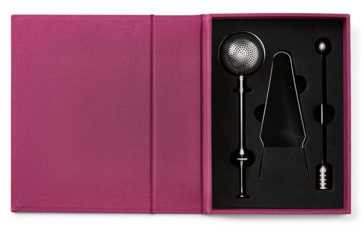 The PrintWorks Tea Tool Set includes a stainless steel tea infuser, metal tongs, and a stirring stick, each in its own slot within black foam, all packaged in a pink box—an ideal kit for tea enthusiasts.