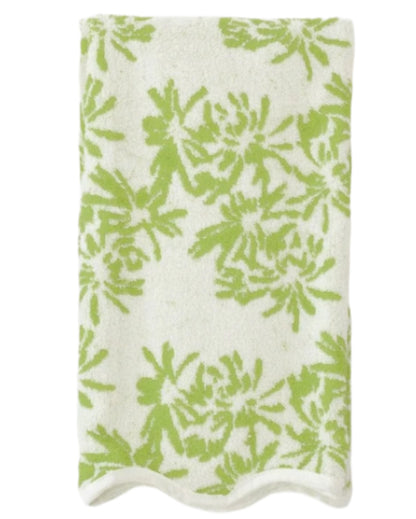 A folded white towel with a green floral design and scallop trim from the Weezie Towels x Meg Braff Bath Collection evokes a Palm Beach summer.