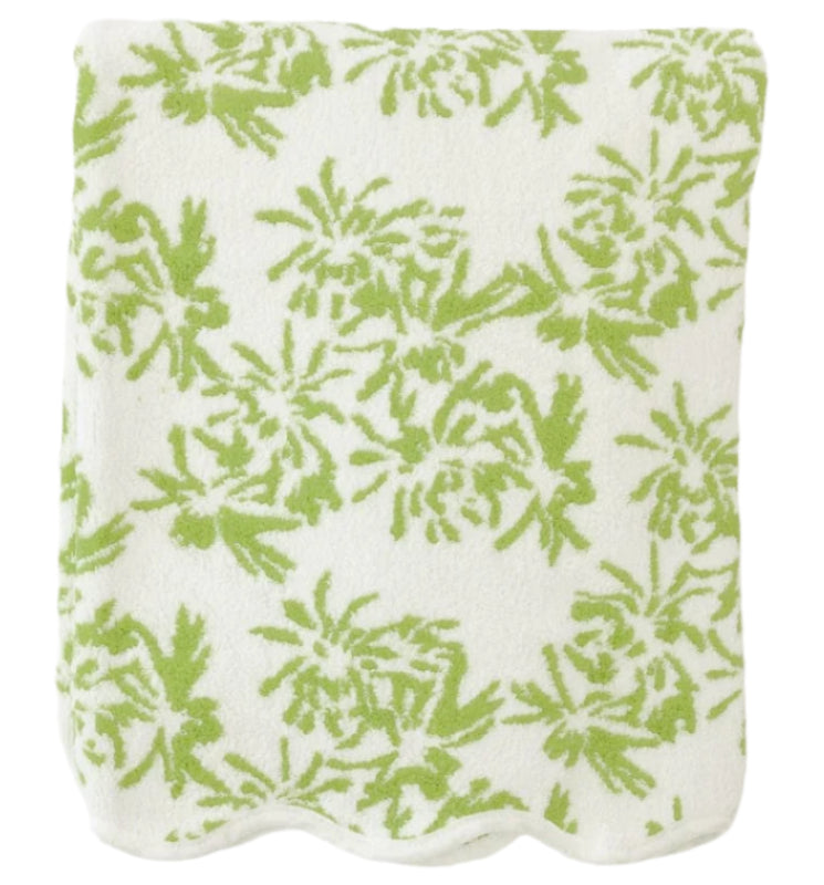 A neatly folded towel from the Weezie Towels x Meg Braff Bath Collection, featuring a green floral pattern and scallop trim, exudes Palm Beach elegance.