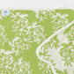 A beautifully folded green towel features a white floral pattern and scallop trim, with a small "Weezie" tag in the corner. This elegant piece is part of the exclusive Weezie Towels x Meg Braff Bath Collection, adding Palm Beach charm to your space.