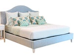 Lee Industries Flair King Bed in light blue upholstery with an arched headboard, styled with patterned green and blue accent pillows.