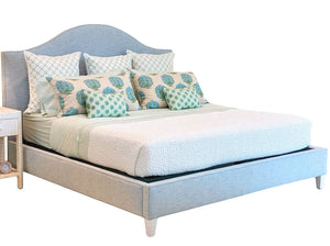 Lee Industries Flair King Bed in light blue upholstery with an arched headboard, styled with patterned green and blue accent pillows.