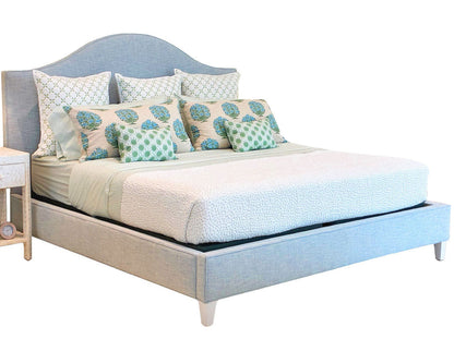 Lee Industries Flair King Bed in light blue upholstery with an arched headboard, styled with patterned green and blue accent pillows.