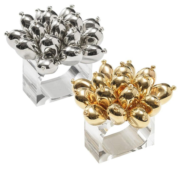 The Kim Seybert Jubilee Napkin Rings feature two sculptural designs with balloon-like clusters, resembling elegant napkin rings. One is crafted in silver and the other in gold, both beautifully set on clear square bases, making them perfect for a sophisticated table setting.