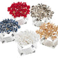 Five Aster Napkin Rings by Kim Seybert, in red, silver, blue, clear, and gold crystal clusters on clear square bases, form a sparkling semicircle for dazzling table decor.
